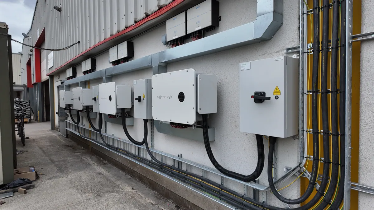 Four Sigenergy inverters with electrical isolators and cable routes on a wall.
