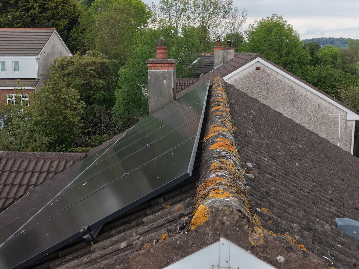 Side view of solar panels and their mounting profile above roof tiles.