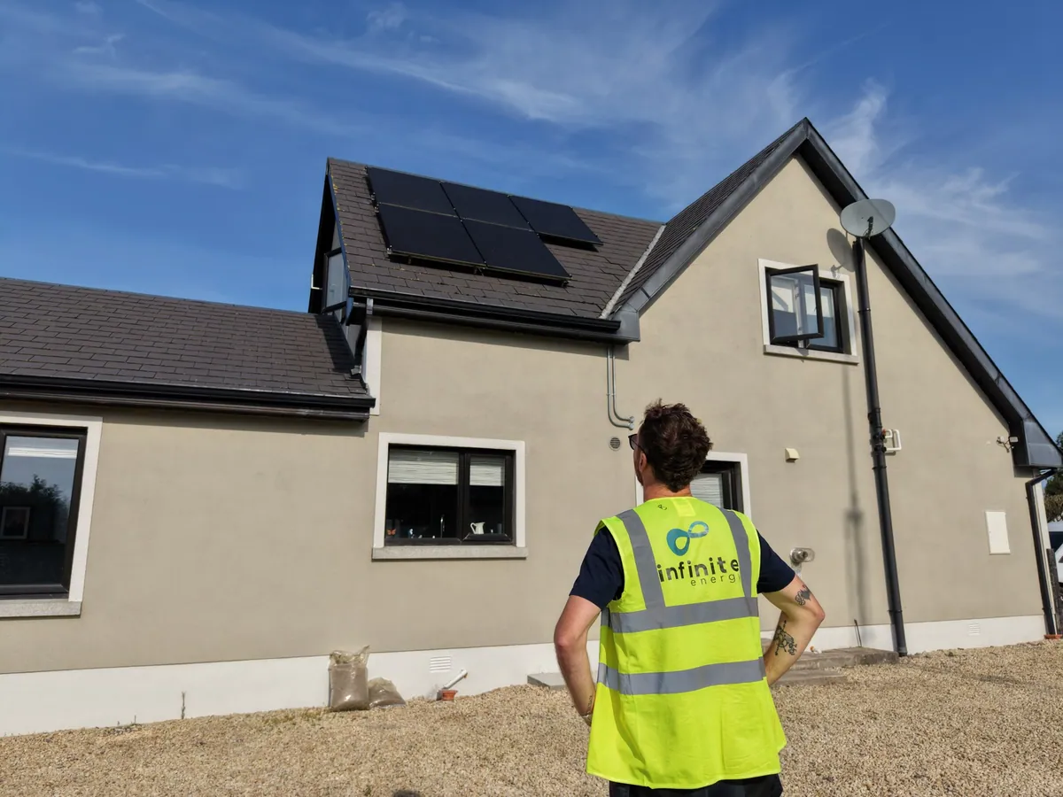 An Infinite Energy installer looking towards solar panels on the roof of a home
