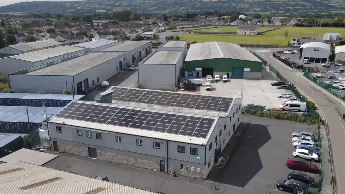 Aerial view of solar panels on the roof of an industrial building, with surrounding commercial units.
