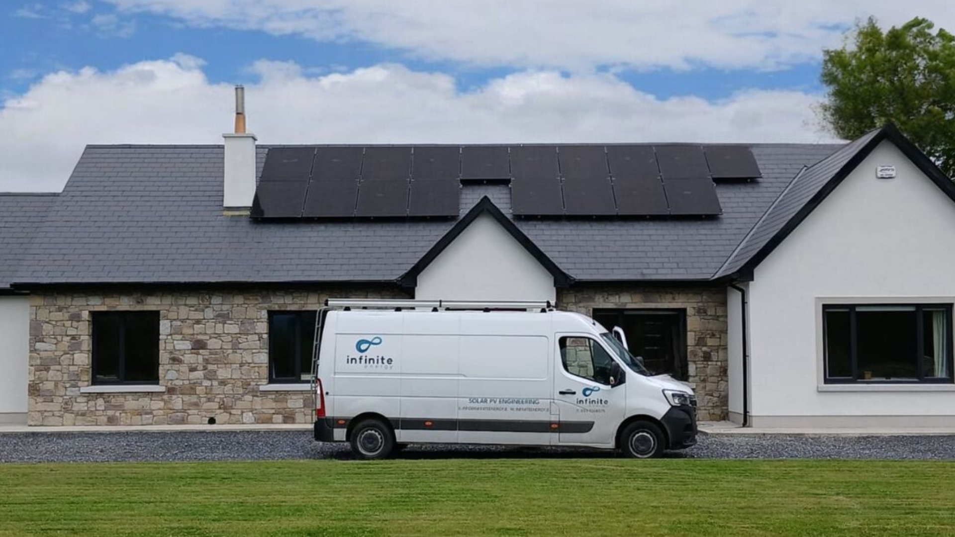 Solar panels on the roof of a detached house, with an Infinite Energy van parked outside.
