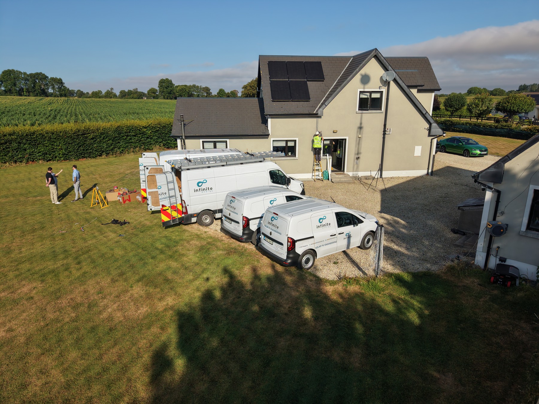 Infinite Energy vans outside an Irish home with rooftop solar panels